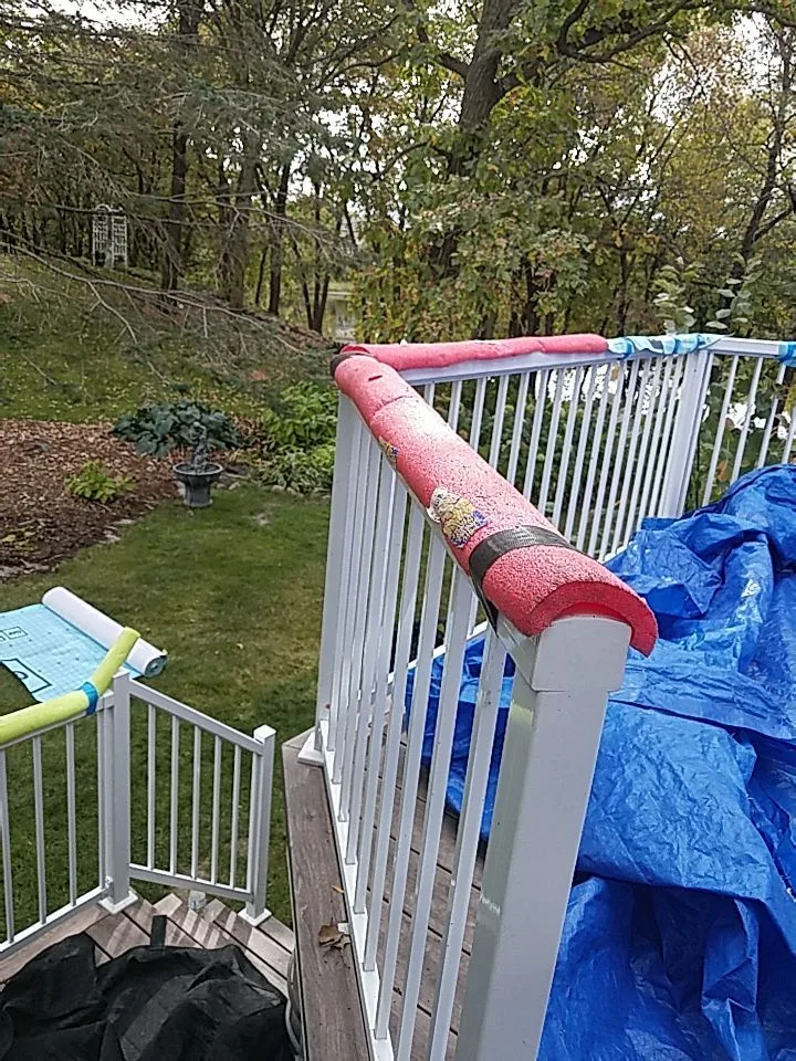 A deck covered with protective sheathing and tarps along the railing