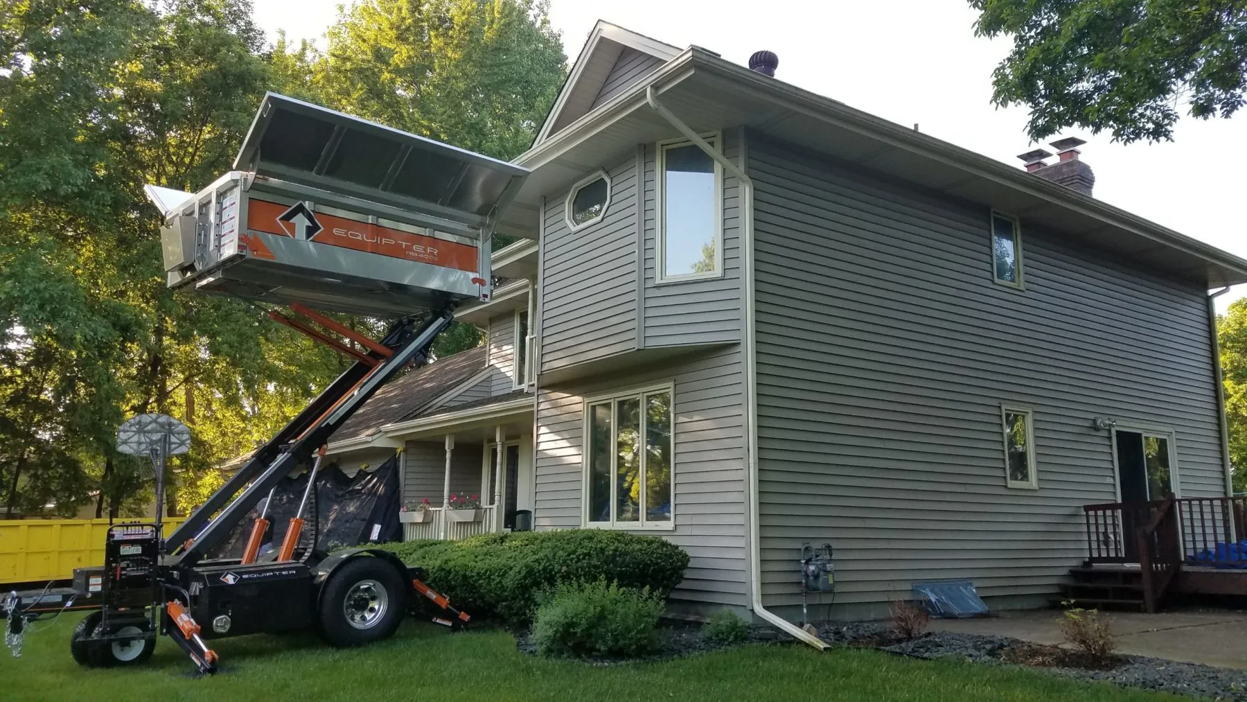 An Equipter raised beside a house to collect roof tear-off debris
